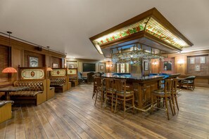 A bar area with wooden flooring, leather seating, and a bar counter with stools. - Radisson Hotel Jalandhar Grand Windsor Resorts Ltd (Jalandhar)