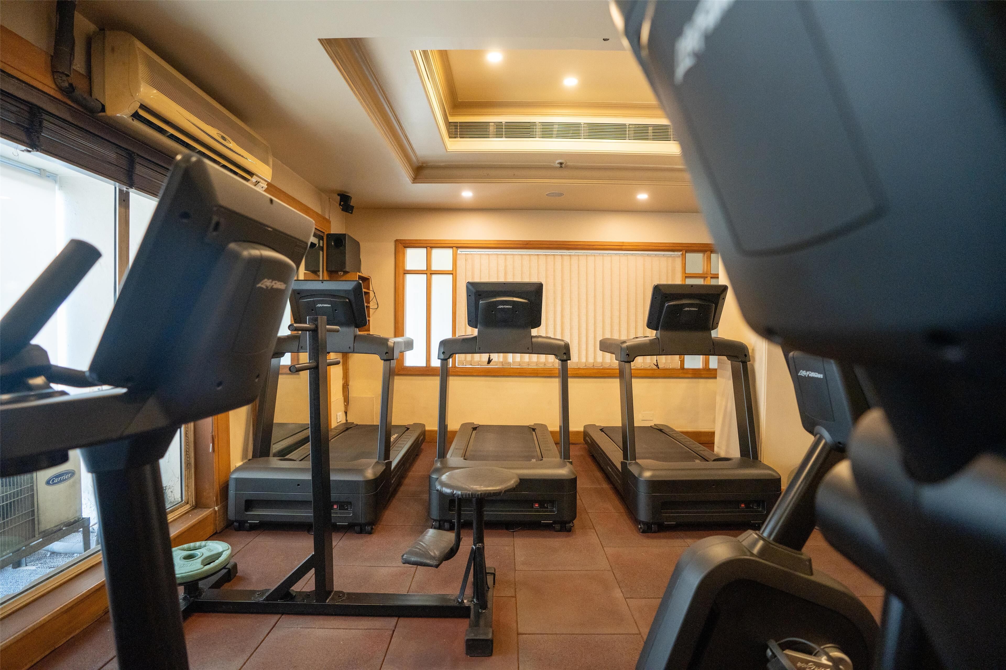 Un gimnasio con cintas de correr, una bicicleta estática y una máquina de remo.