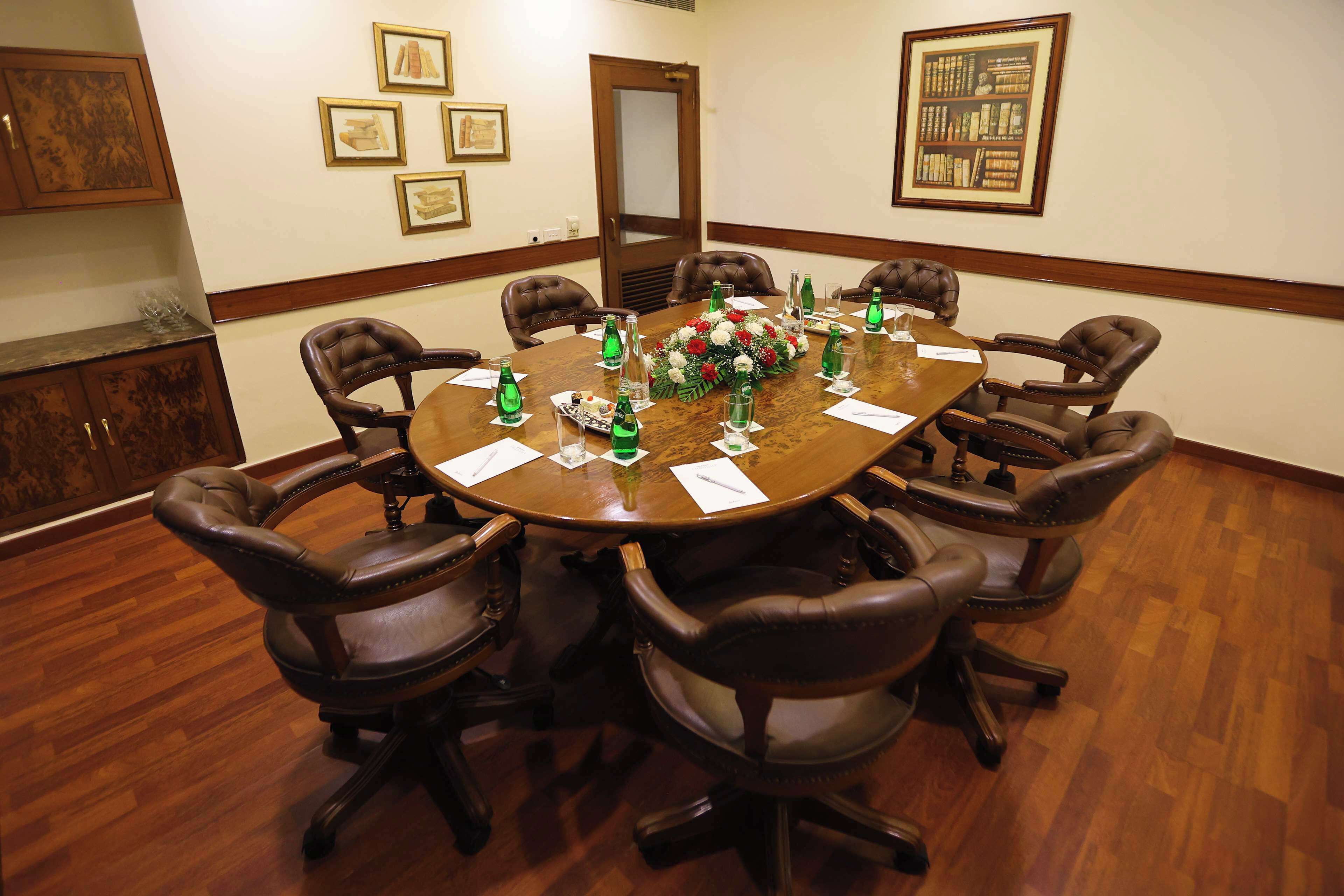 A conference room with a round table, leather chairs, and a floral centerpiece.