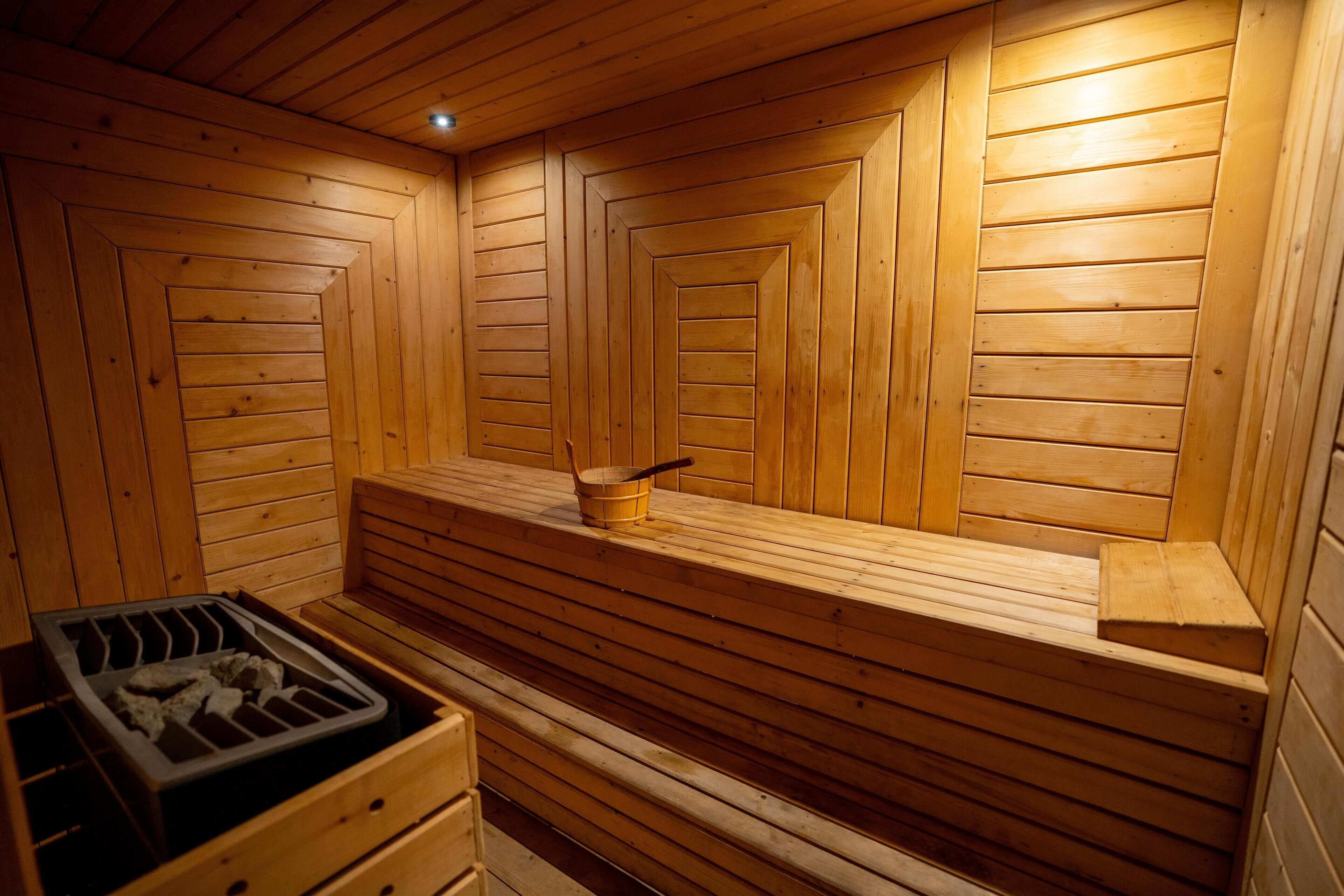 A wooden sauna with benches and a wooden bucket.