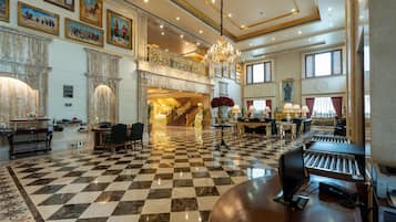A spacious lobby with a checkered floor, a grand staircase, and a chandelier.