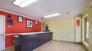 Un espace d’accueil avec un comptoir, des tableaux encadrés et une horloge au mur.