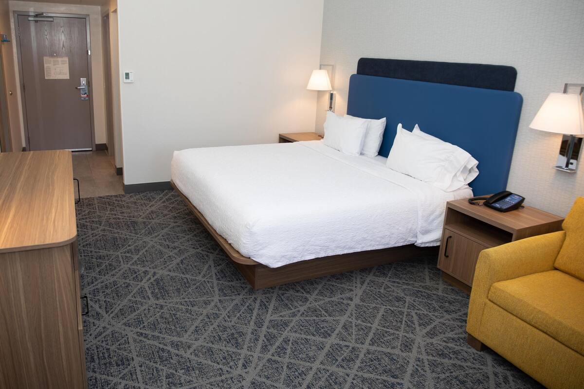 Ein Hotelzimmer mit Bett, Nachttischlampen, Schreibtisch und Stuhl.
