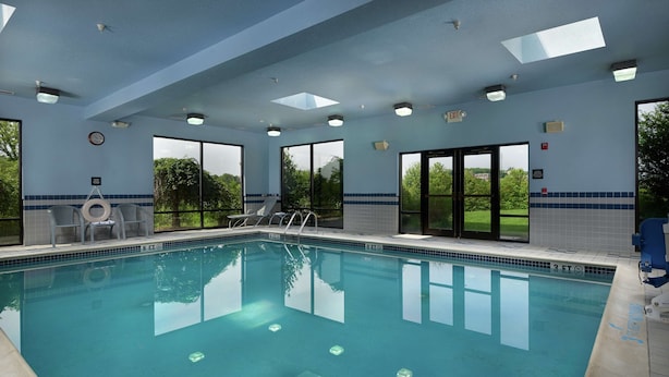 An indoor swimming pool with clear blue water, large windows, and a view of greenery outside. - Hampton Inn Shrewsbury (New Freedom)