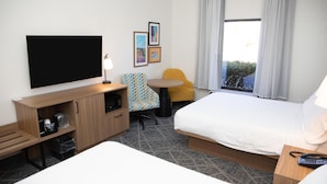 A hotel room with a bed, a desk with a TV, a chair, a small table, and a window with curtains. - Hampton Inn Shrewsbury (New Freedom)