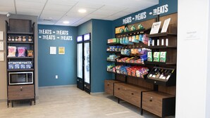 A treats shop with shelves stocked with snacks and beverages, a microwave, and a refrigerator. - Hampton Inn Shrewsbury (New Freedom)