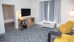 A hotel room with a bed, a desk with a flat-screen TV, a chair, a heater, and a window with curtains. - Hampton Inn Shrewsbury (New Freedom)