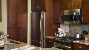 A kitchen with stainless steel appliances, granite countertops, and wooden cabinets. - Oakwood River Oaks North (Rochester)