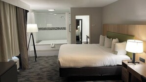 A hotel room with a large bed, bedside table, lamp, and a view of the bathroom. - Country Inn & Suites by Radisson, Bakersfield, CA (Bakersfield)