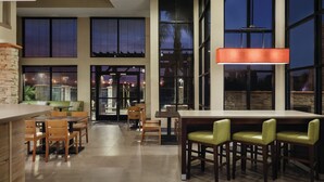 A modern dining area with a long table and multiple chairs, large windows, and a hanging light fixture. - Country Inn & Suites by Radisson, Bakersfield, CA (Bakersfield)