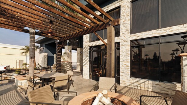 An outdoor patio area with tables and chairs, a fire pit, and a pergola structure. - Country Inn & Suites by Radisson, Bakersfield, CA (Bakersfield)