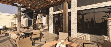 An outdoor patio area with tables and chairs, a fire pit, and a pergola structure.