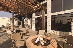 An outdoor patio area with tables and chairs, a fire pit, and a pergola structure. - Country Inn & Suites by Radisson, Bakersfield, CA (Bakersfield)