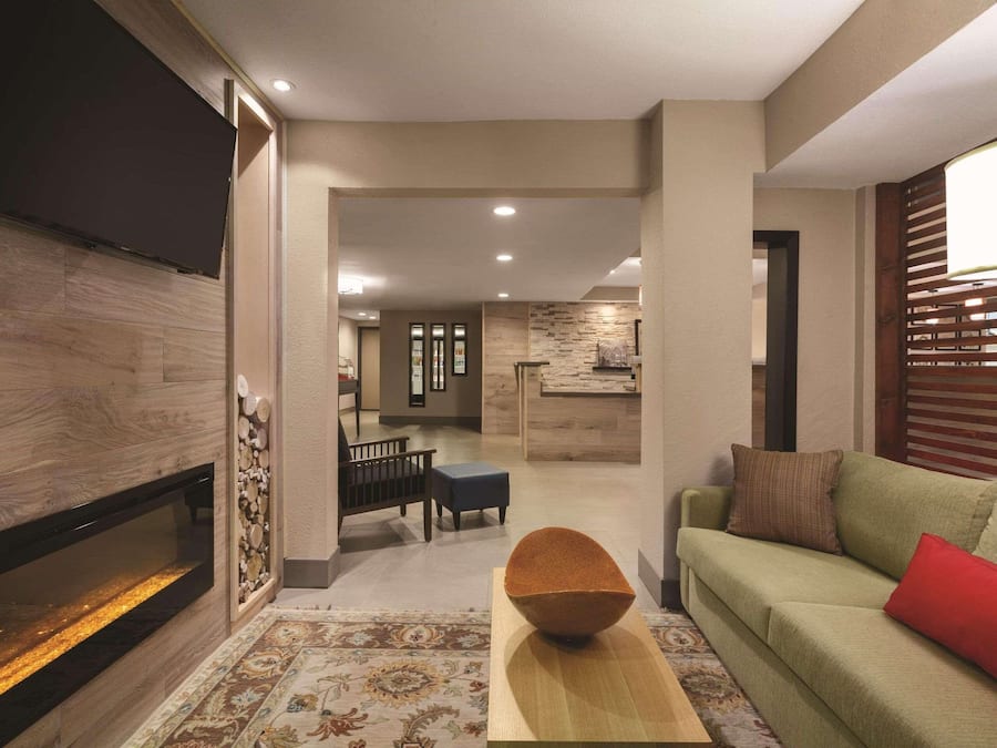 A modern living room with a fireplace, a green sofa, and a dining area in the background.