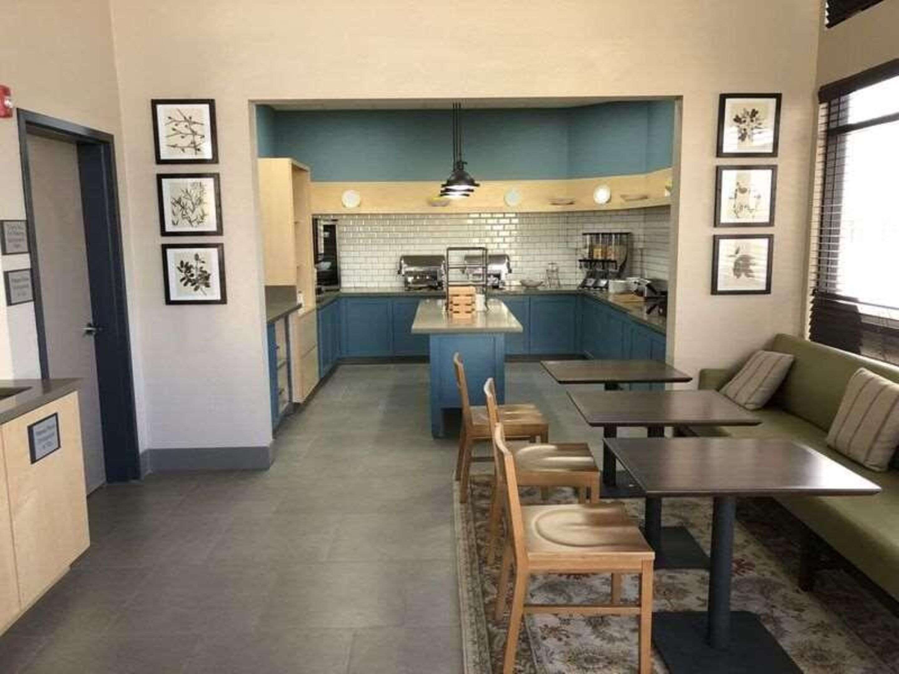 A compact kitchen with a central island, a dining area with a sofa and chairs, and framed artwork on the walls.