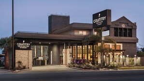 A Country Inn & Suites building with a modern design, featuring a prominent entrance, a landscaped front yard, and a signboard. - Country Inn & Suites by Radisson, Bakersfield, CA (Bakersfield)