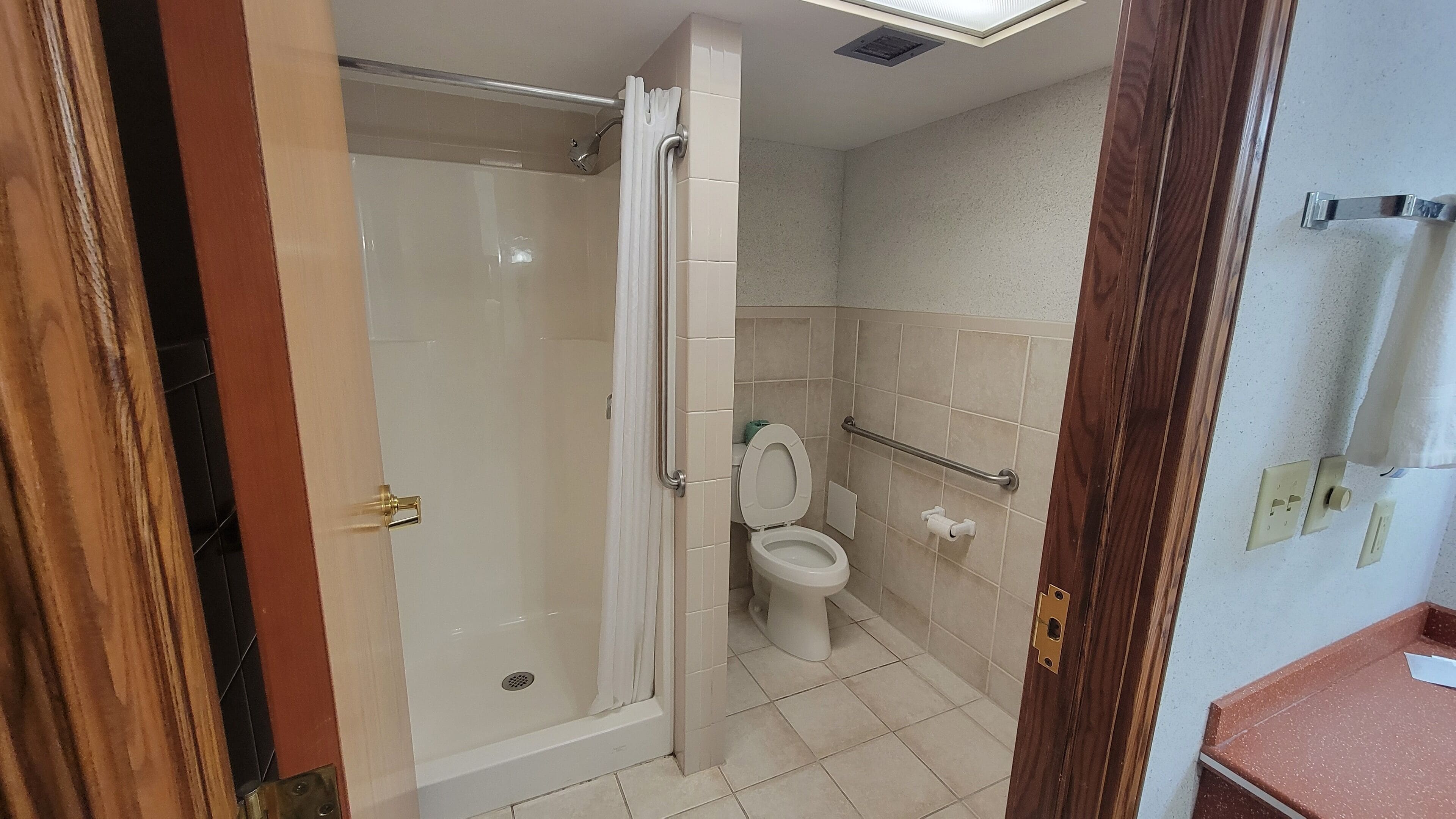 A bathroom with a glass-enclosed shower, a toilet, and a sink.