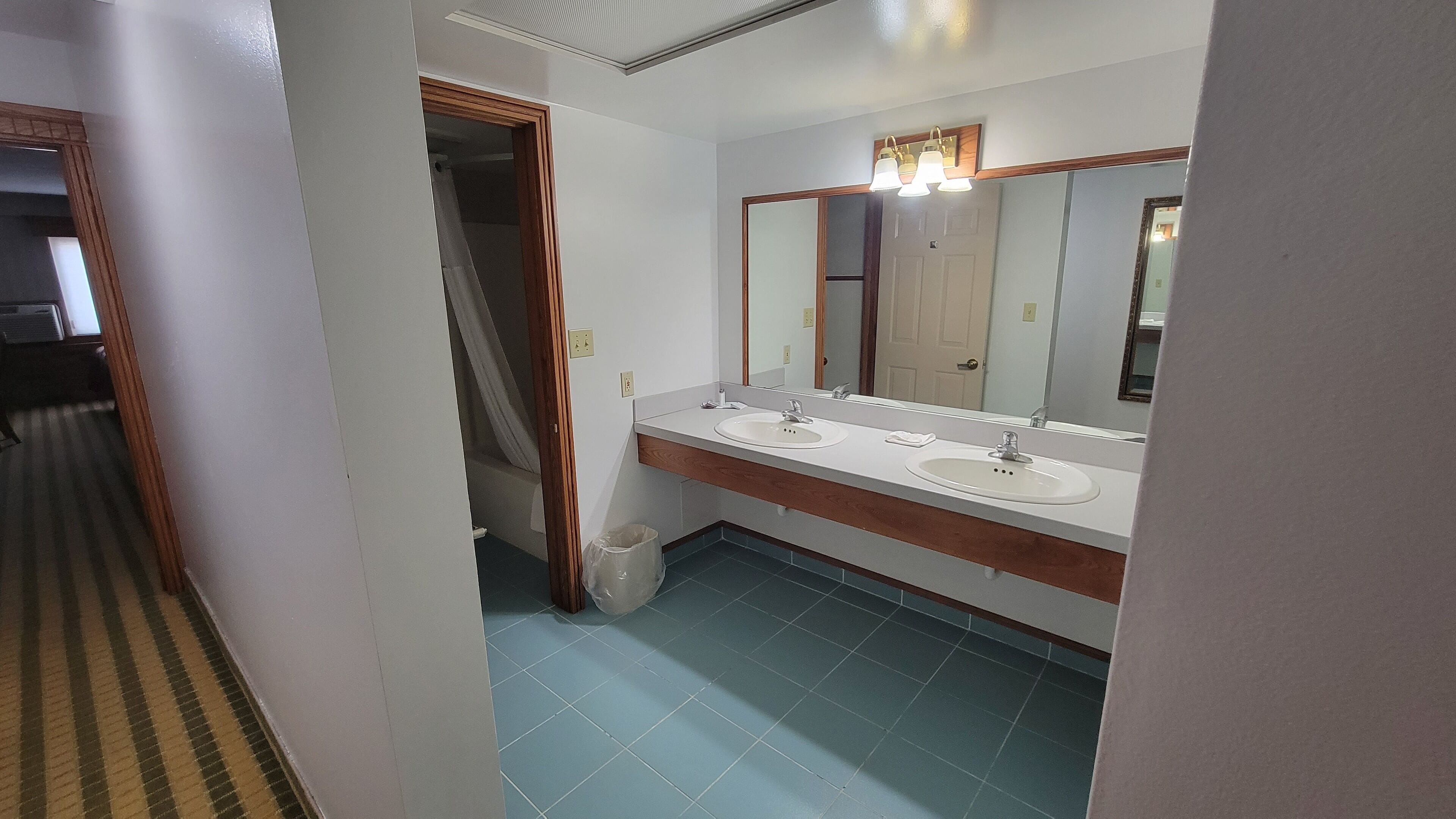 Une salle de bain avec deux lavabos, un miroir et un luminaire placé au-dessus du miroir.