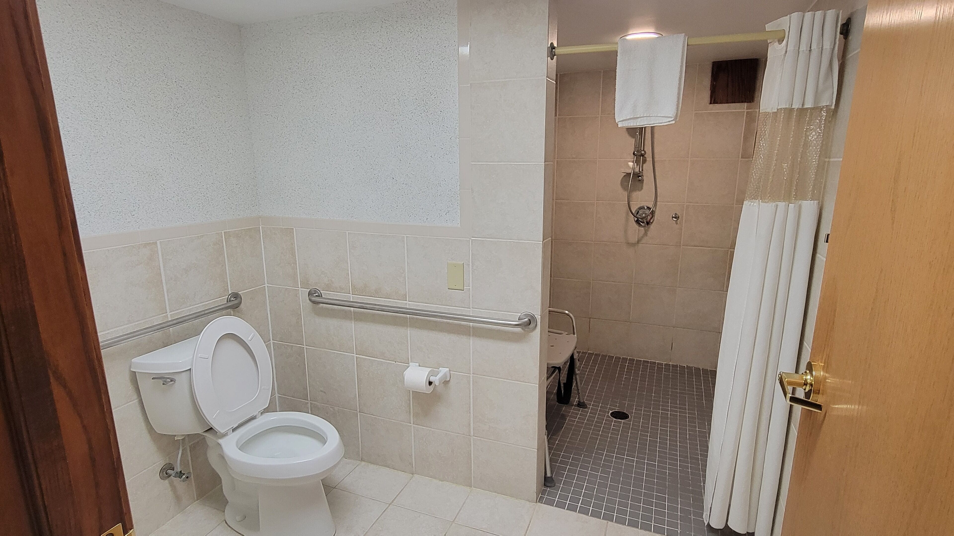 A bathroom with a toilet, a shower, and a towel rack.