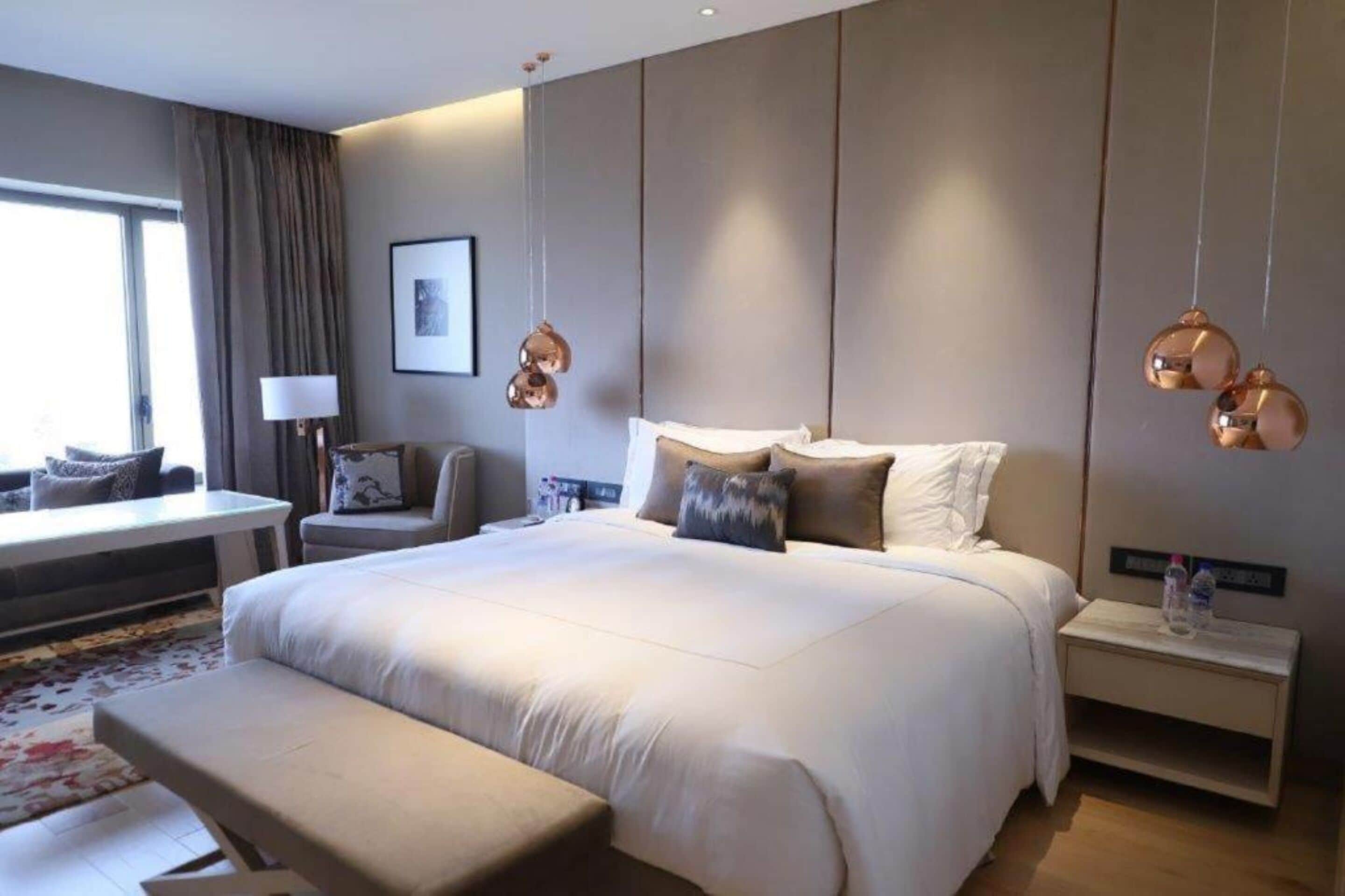 Una habitación de hotel moderna con una cama grande, un escritorio, una silla y una mesita de noche.