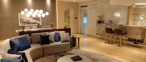 A modern living room with a sofa, coffee table, and a dining area with chairs.