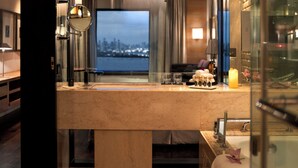 A modern bathroom with a large mirror, a bathtub, and a view of a cityscape.