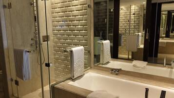 A modern bathroom with a glass shower enclosure, a large mirror, and a bathtub.