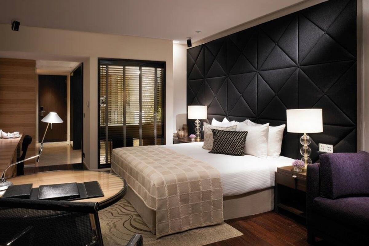 A modern hotel room with a large bed, a seating area with a table, and a separate armchair.