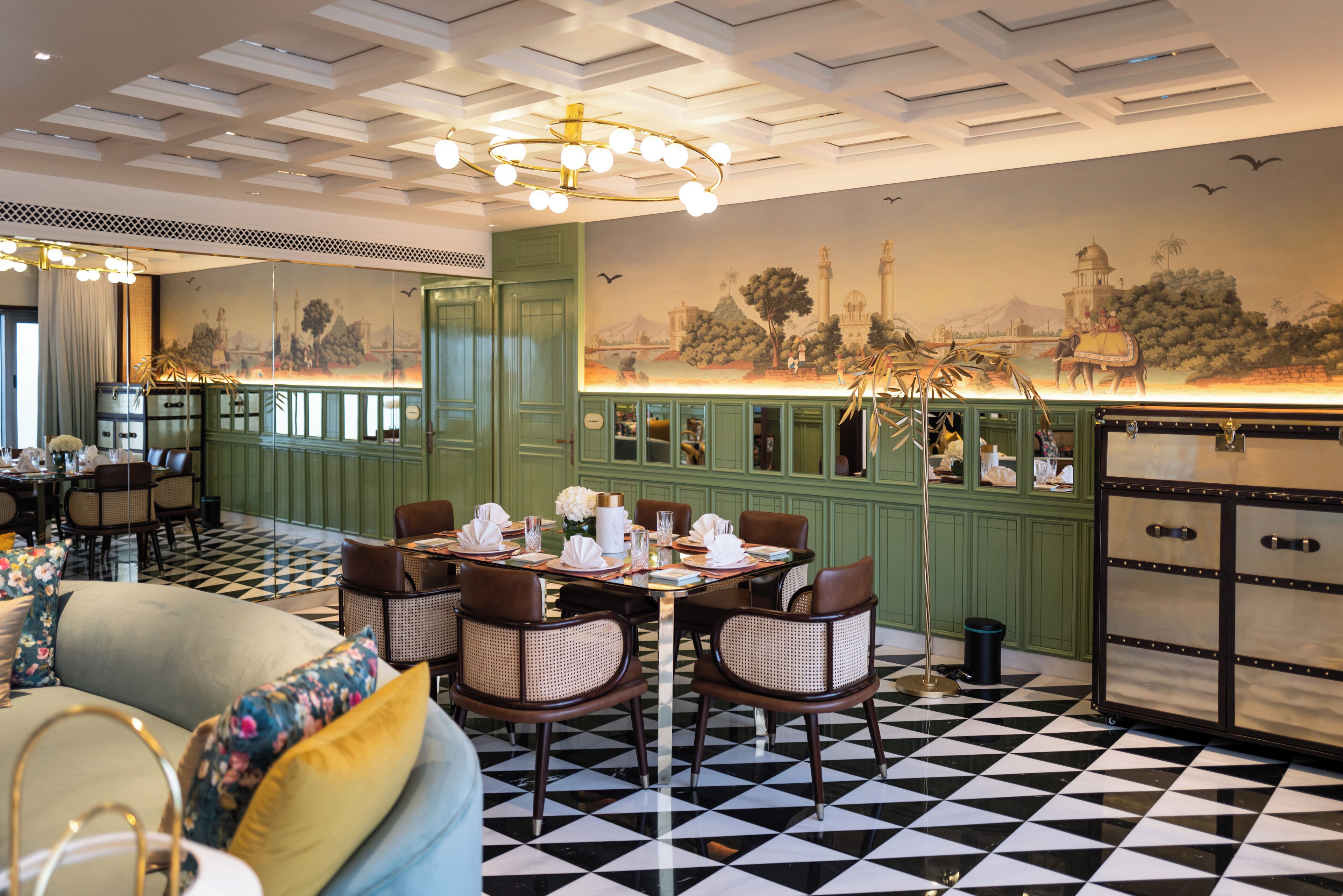 Comedor con piso a cuadros, paneles verdes y un mural que representa una escena histórica.