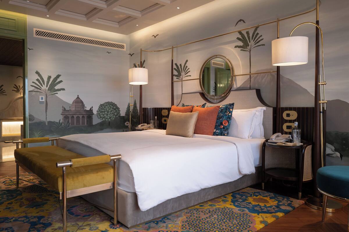 A spacious bedroom with a large bed, a bedside table, a chair, and a decorative wall mural.