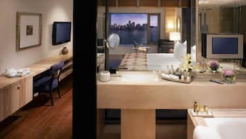 Una habitación de hotel moderna con una cama grande, un escritorio, un baño con bañera, un televisor y vistas a la ciudad.