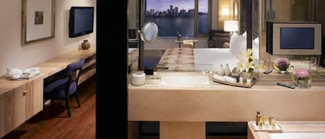 Una habitación de hotel moderna con una cama grande, un escritorio, un baño con bañera, un televisor y vistas a la ciudad.