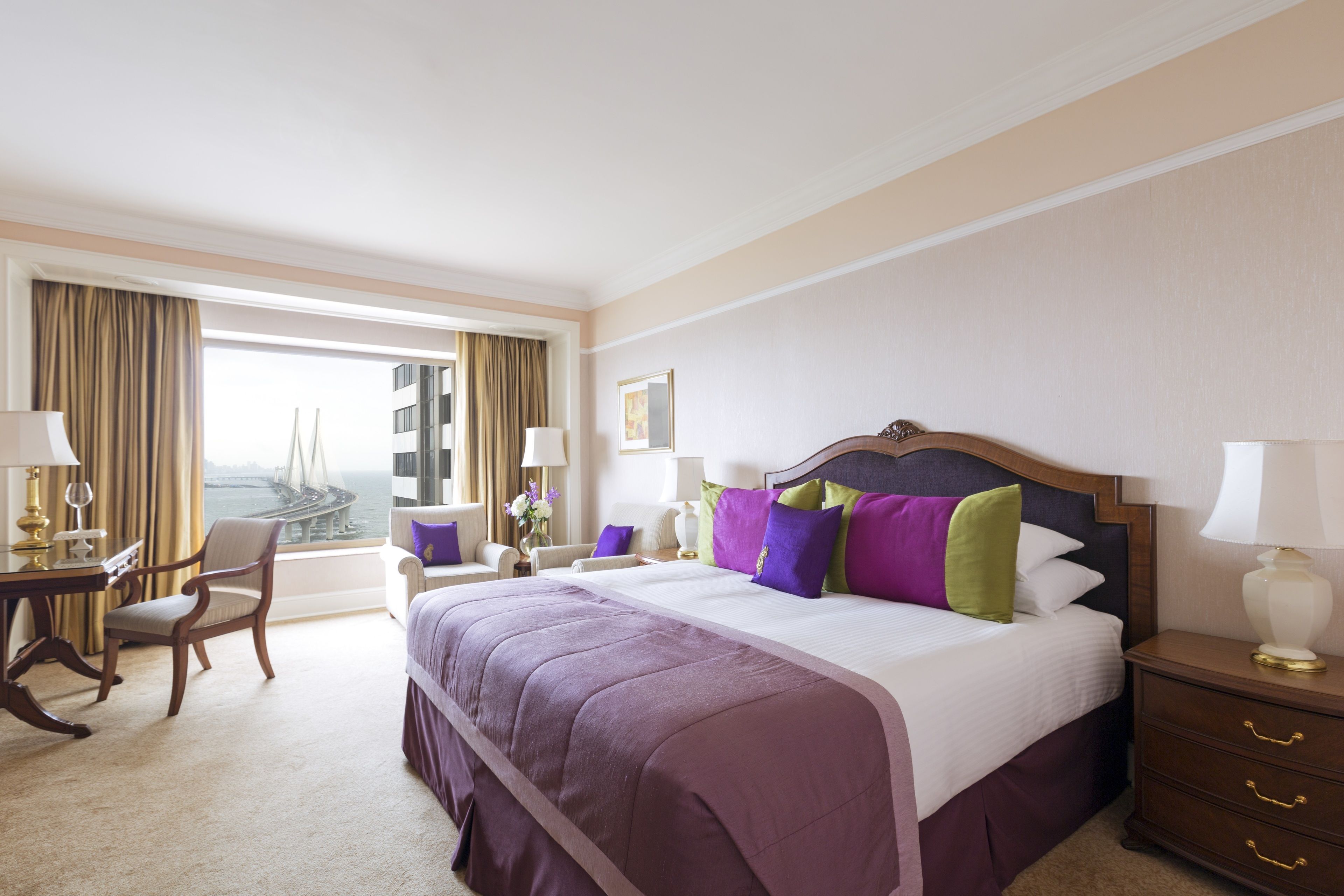 Ein Hotelzimmer mit einem großen Bett, einem Schreibtisch, einem Stuhl und Blick auf eine Brücke.