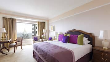 Ein Hotelzimmer mit einem großen Bett, einem Schreibtisch, einem Stuhl und Blick auf eine Brücke.