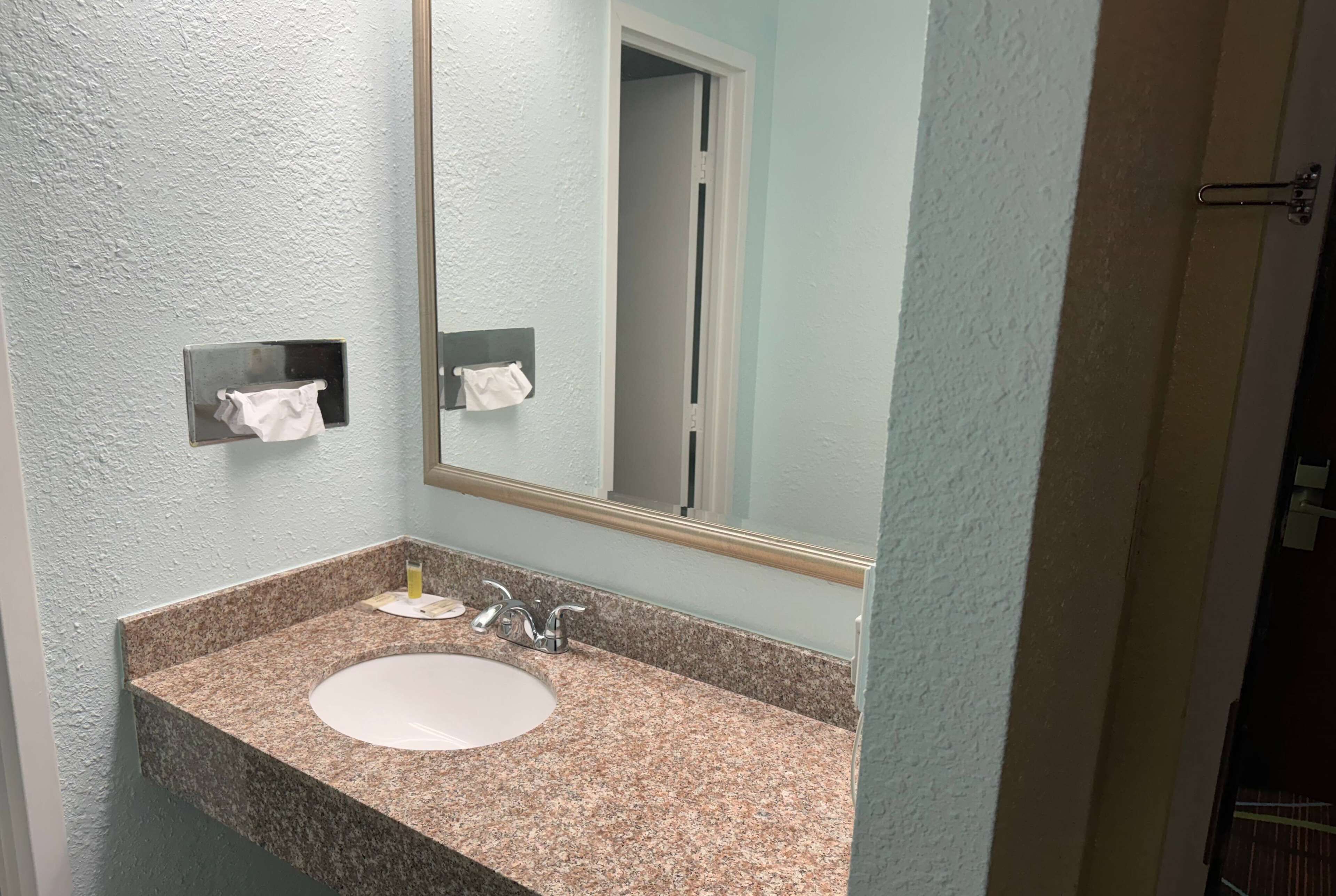 Een badkamer met een wastafelblad van graniet, een spiegel en twee handdoekdispensers.