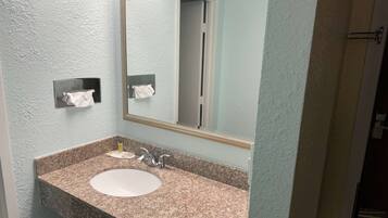 Een badkamer met een wastafelblad van graniet, een spiegel en twee handdoekdispensers.