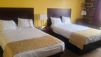 Une chambre d’hôtel avec deux lits, chacun agrémenté de linge de lit blanc et d’un détail doré. On y trouve une table de chevet avec une lampe et une horloge, ainsi qu’un mur en briques avec une fenêtre et des rideaux.