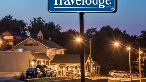 A Travelodge hotel with a sign, parking lot, and buildings in the background.