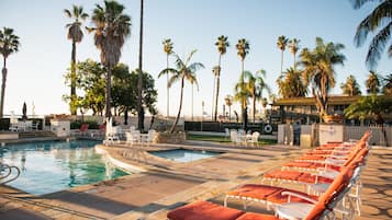 A pool area with lounge chairs and palm trees.