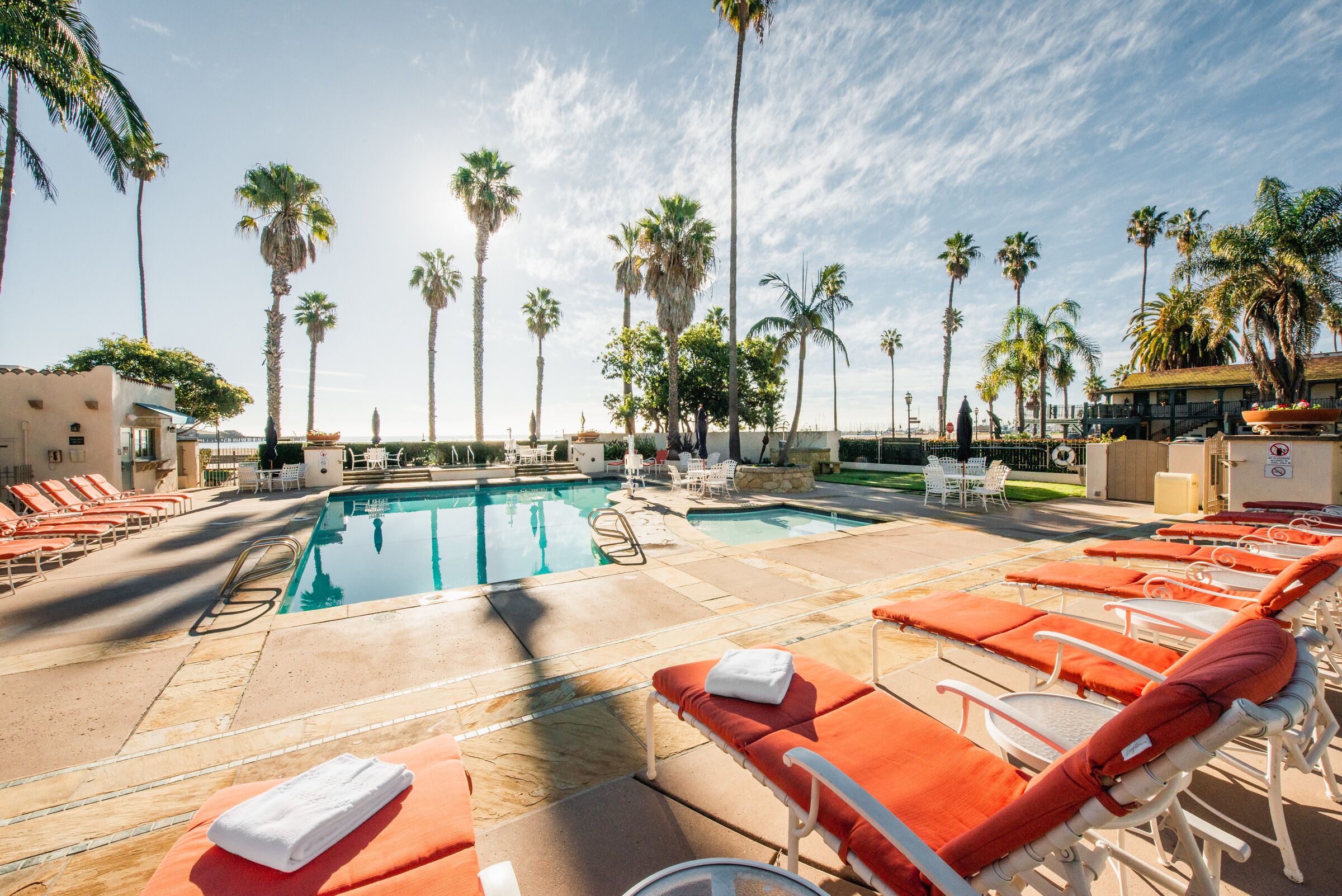 A pool area with lounge chairs and palm trees.