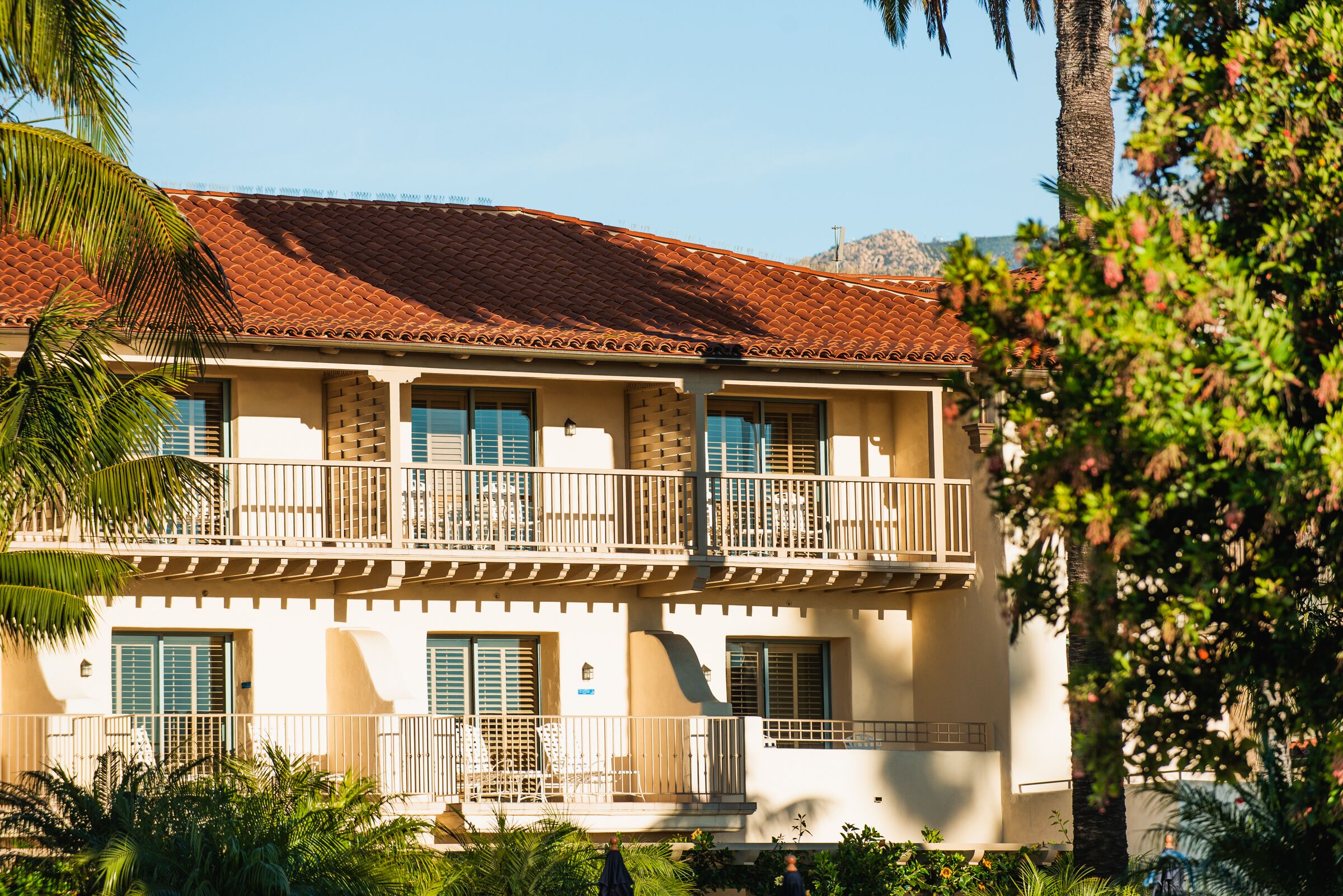 A two-story building with a red-tiled roof, balconies, and a white facade.