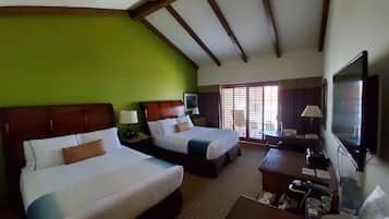 Een hotelkamer met twee bedden, een televisie, een bureau en een raam met zonwering.