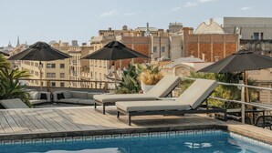 A rooftop pool area with lounge chairs and umbrellas, surrounded by city buildings. - Claris Hotel & Spa 5*GL, a Small Luxury Hotels of the World (Barcelona)
