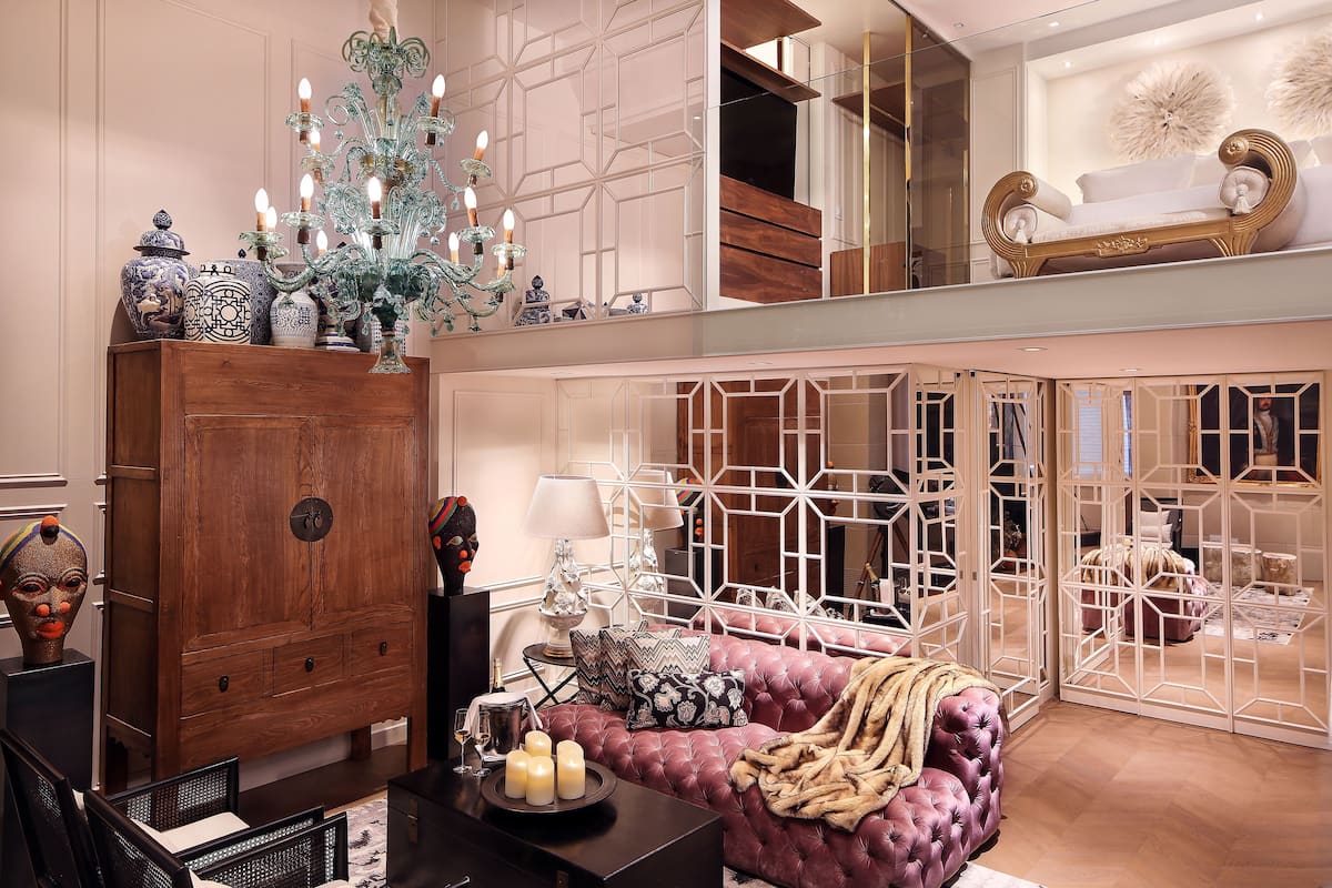 A spacious living area with a large wooden cabinet, a plush red sofa, and a decorative chandelier.
