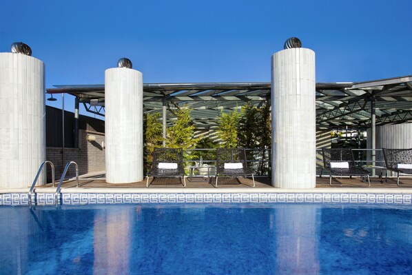 Relax by the pool surrounded by a glass roof structure and patterned tile edge.