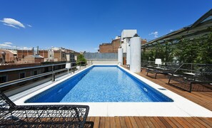A rooftop swimming pool with a wooden deck and lounge chairs, surrounded by buildings. - Claris Hotel & Spa 5*GL, a Small Luxury Hotels of the World (Barcelona)