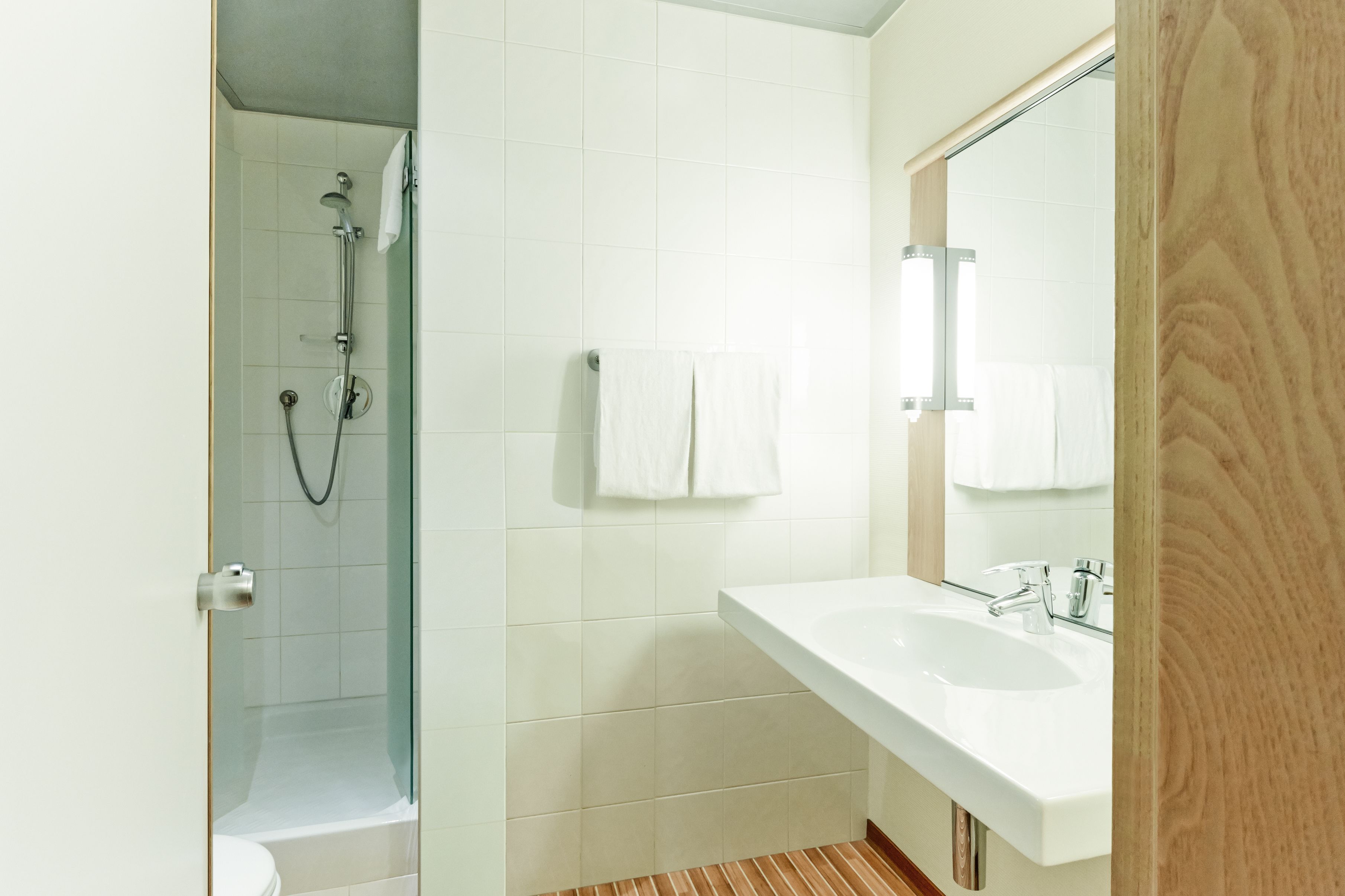 Une salle de bain moderne avec une douche à parois de verre, un lavabo blanc et un grand miroir.