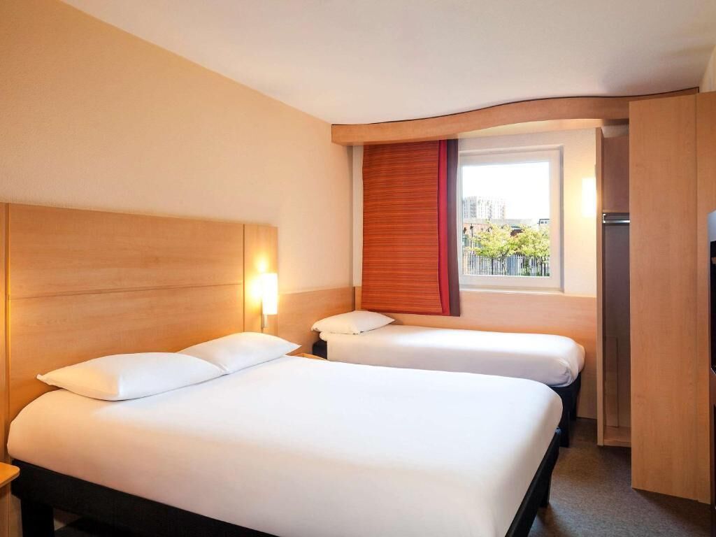 A hotel room with two beds, a window with a view, and a door leading to a balcony.