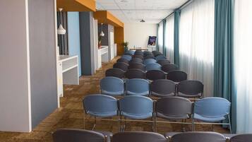 A conference room with rows of chairs, a whiteboard, and a projector screen.