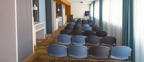 A conference room with rows of chairs, a whiteboard, and a projector screen.